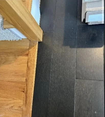 Where new dark hardwood meets the oak edge of a stair landing